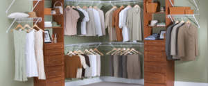Organized walk-in closet with clothes neatly hung and wooden furniture.