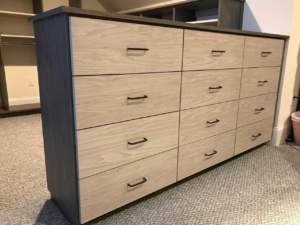 A wooden dresser with multiple drawers in a carpeted room.