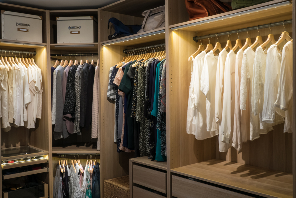 A neatly organized walk-in closet with clothes hung on hangers and shelves with storage boxes.