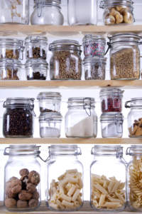 Organized pantry shelves with various food items stored in clear glass jars.