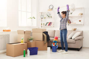 Woman packing or unpacking belongings with moving boxes in a living room.