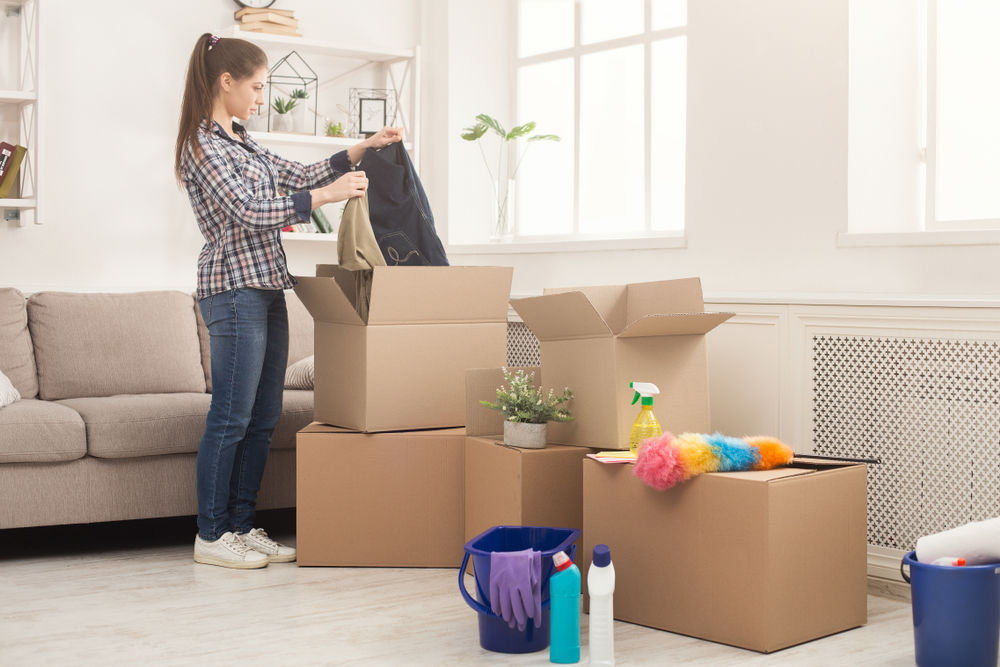 A woman unpacking boxes in a bright living room setting.