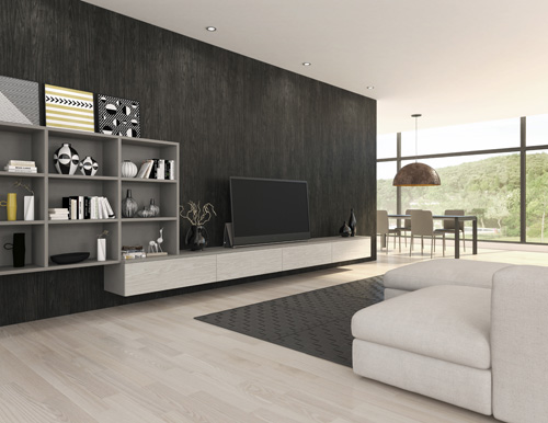 Modern living room with a minimalist design, featuring a white sofa, dark shelving, and a wide-screen tv, with large windows offering a view of the outdoors.