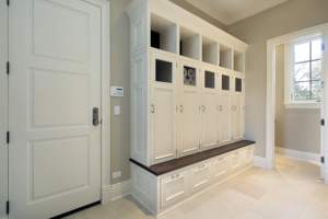 A clean and organized mudroom with built-in storage cabinets and a bench.