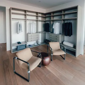 Modern custom closet with neatly organized clothing and sitting area.