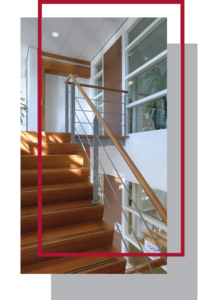 Modern staircase with wooden steps and stainless steel balustrade in a brightly lit interior featuring a custom closet.