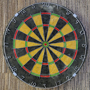 A well-used dartboard with visible wear marks, stored in a custom closet.