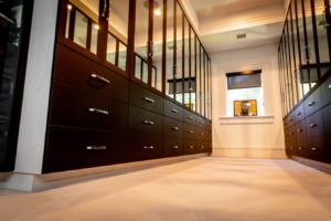 Modern walk-in closet with dark wood cabinetry and a sleek design.