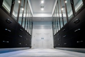 Modern walk-in closet with symmetric black cabinets and a white door at the end.
