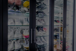 A collection of various sneakers organized in a shoe storage cabinet with glass fronts.
