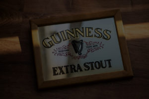 Framed Guinness Extra Stout advertisement on a wooden surface for custom man caves.