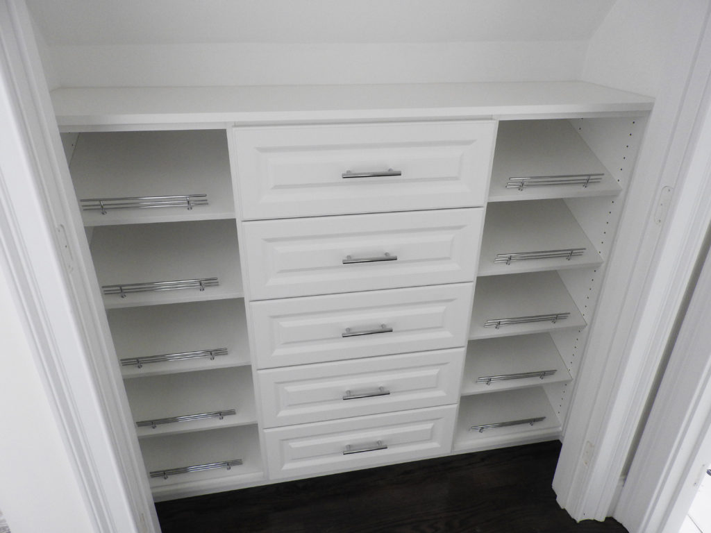 A white built-in kid's closet with drawers and shelves in an empty room.