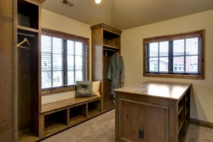 A well-lit, cozy dressing area with wooden furniture and blinds on the windows.