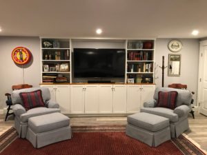 A cozy living room with two armchairs, custom entertainment centers, and bookshelves.