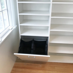 An open empty drawer in a white built-in shelving unit next to a window with wooden flooring, designed for kid's closets.