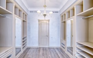 Empty walk-in closet with built-in shelves and a central door.