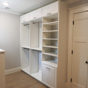 A white built-in closet with open shelves and drawers in a modern room.