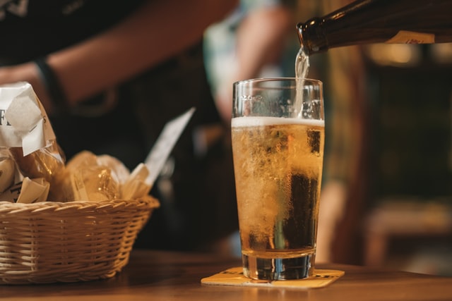 Pouring beer into a glass in a custom man cave with snacks in the background.