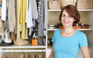 A smiling woman standing in front of an organized closet filled with clothes and accessories.