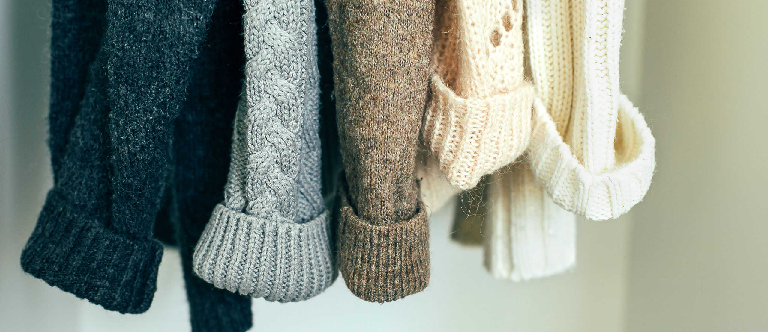 Knitted clothes sweater hanging in the closet. Cozy autumn winter