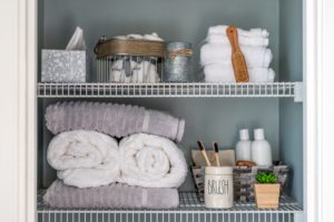 A neatly organized bathroom shelf with organization of towels and toiletries.