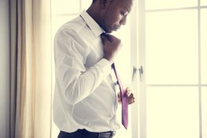 A man in work clothes, adjusting his red tie.