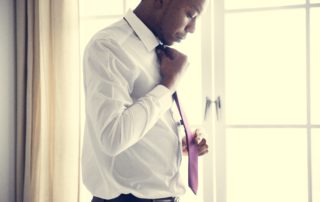 A man in work clothes, adjusting his red tie.