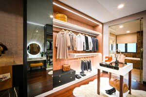 An organized walk-in closet with neatly arranged clothes and accessories, featuring a central island for added organization and a full-length mirror.