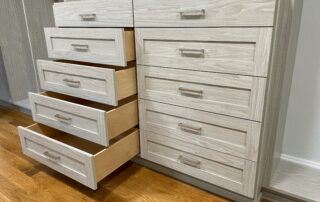 A light wooden closet dresser with multiple open drawers.