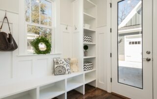 Bright mudroom with built-in bench and storage, looking out towards a driveway.