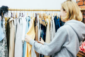Woman browsing through clothing stored on a rack in a store.