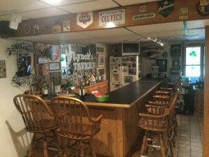 A well-stocked, cozy Man Cave with wooden chairs and sports-themed decor.