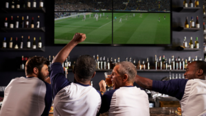 Sports fans celebrating in a Man Cave while watching a soccer match on television.