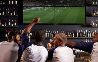 Sports fans celebrating in a Man Cave while watching a soccer match on television.