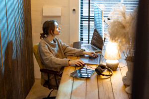 Woman working on a laptop in a cozy home office environment.