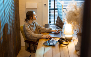 Woman working on a laptop in a cozy home office environment.