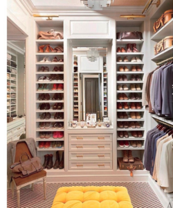 A well-organized walk-in closet featuring an array of shoes, clothing, and a vanity area with efficient shoe storage solutions.
