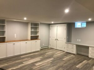 Modern basement interior with an entertainment center, built-in cabinets, and shelving.