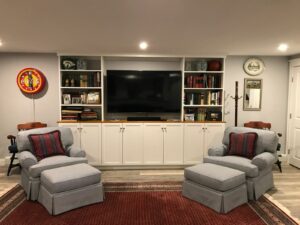 A cozy living room setup with two armchairs, a large entertainment center, and shelving with books and decor.