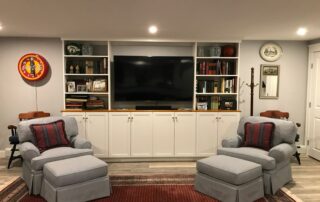 A cozy living room setup with two armchairs, a large entertainment center, and shelving with books and decor.