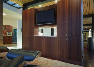 Modern living room with dark wood cabinetry and an entertainment center featuring a flat-screen TV mounted on the wall.
