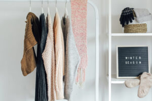 A cozy selection of organized winter clothing and accessories neatly arranged in a home environment with a sign that reads "winter season.