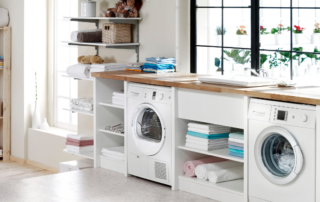 A bright laundry room with a washer, dryer, and neatly organized shelves in the laundry rooms.