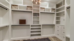 A neat and organized walk-in closet with empty shelves, drawers, hanging rods, and closet organizers.