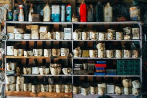 Shelves stocked with old labeled bottles, boxes, and various vintage items in a rustic garage organization setting.