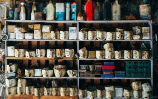 Shelves stocked with old labeled bottles, boxes, and various vintage items in a rustic garage organization setting.