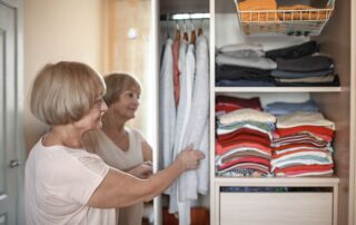 Senior woman organizing clothes in a reach-in closet.