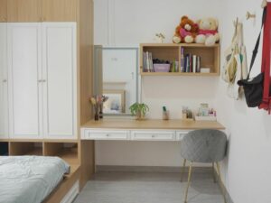 A tidy bedroom with a study area, featuring a desk, chair, bookshelves, plush toys, and mudroom organizers.