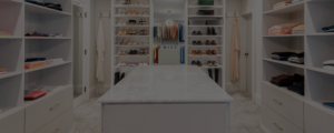 A well-organized walk-in closet with shelving units for shoes and folded clothing, and a central island for additional storage.