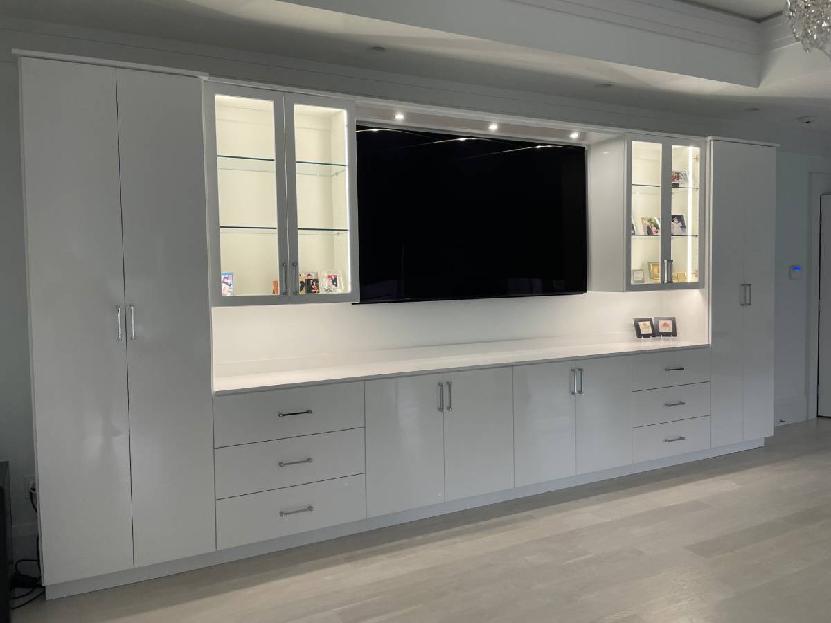 A modern living room custom entertainment center with white cabinets and led lighting.